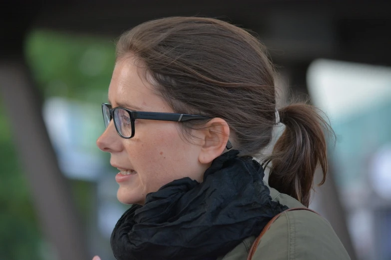 a woman with glasses talking on a cell phone, by Mathias Kollros, flickr, brown hair in a ponytail, close up shot from the side, journalist photo, half - length photo