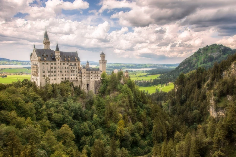 a castle sitting on top of a lush green hillside, by Matthias Weischer, overlooking a vast serene forest, tonemapped, hogwarts, set in ww2 germany