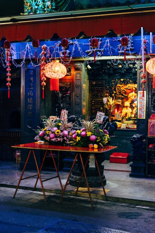 a table that has a bunch of flowers on it, a picture, by John La Gatta, shutterstock, maximalism, chinese temple, night shot, kowloon cyberpunk, stock photo