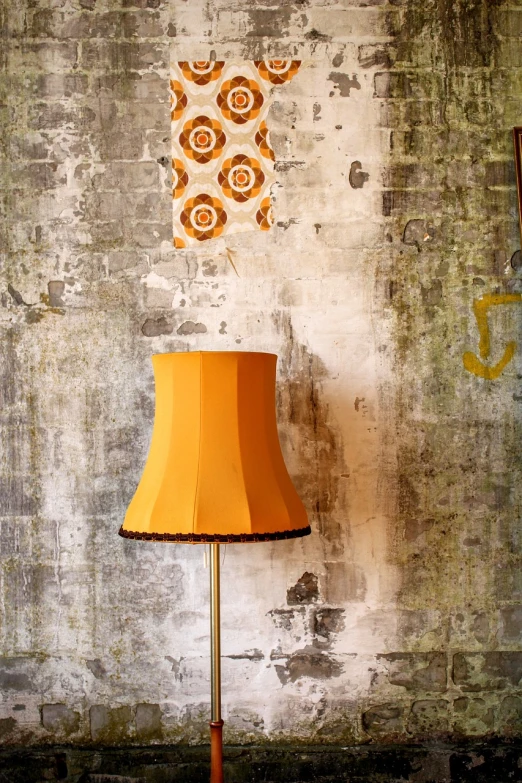 a lamp sitting on top of a wooden floor next to a wall, a portrait, inspired by Pieter de Hooch, baroque, yellow and orange color scheme, vintage showcase of the 60s, seams, inside a frame on a tiled wall