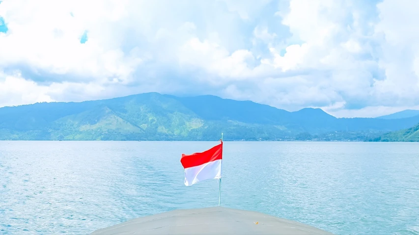 a boat on a body of water with mountains in the background, by Kogan Gengei, shutterstock, sumatraism, holding a white flag, taken on iphone 14 pro, red and white color theme, dlsr photo