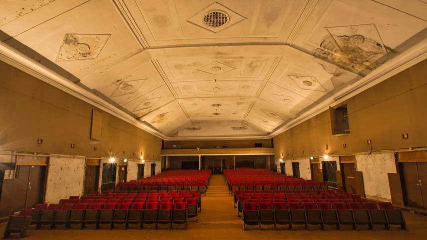 a large room filled with lots of red chairs, by Matthias Stom, flickr, art nouveau, urban exploring, war theatre, symmetrical front view, speakers