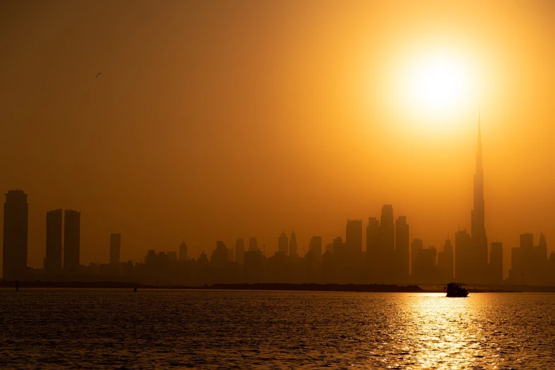 a large body of water with a city in the background, a stock photo, by Jitish Kallat, shutterstock, romanticism, glowing hot sun, during sandstorm, shot on 7 0 mm, backlit!!