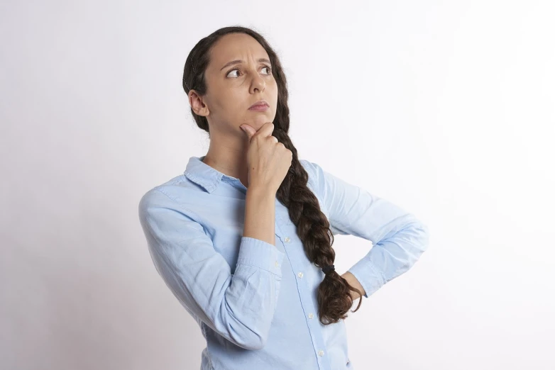 a woman in a blue shirt has her hand on her chin, figuration libre, hovering indecision, woman with braided brown hair, white background : 3, as she looks up at the ceiling