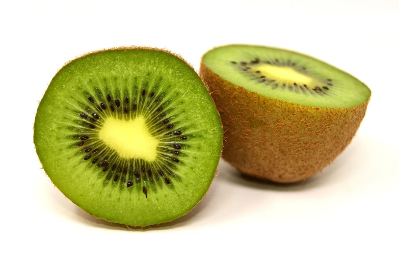 a kiwi fruit cut in half on a white surface, pexels, istockphoto, h 7 0 4, fake, kahikatea