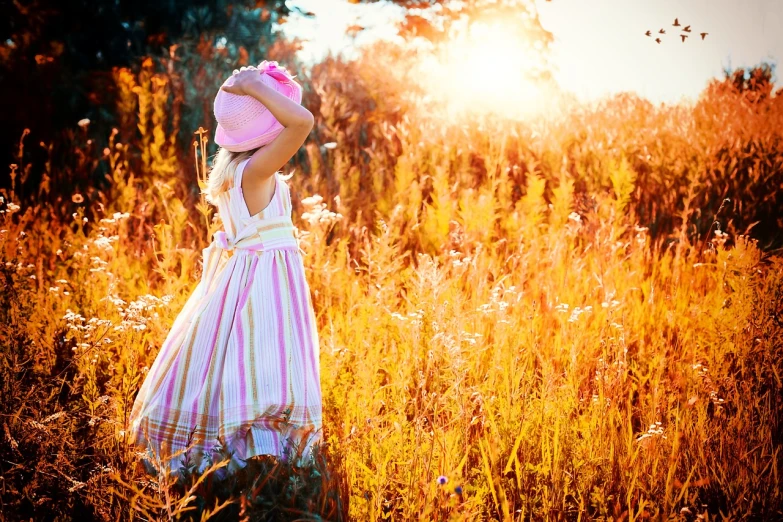 a little girl standing in a field of tall grass, shutterstock, pink sunlight, autumn field, professionally post-processed, in rays of sunlight