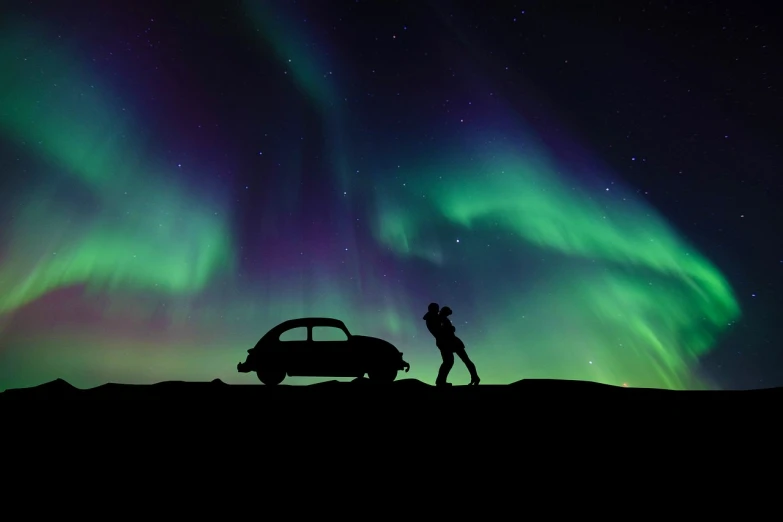 a man standing on top of a hill next to a car, a picture, inspired by roger deakins, pexels contest winner, romanticism, northern lights background, beetle, silhouette, kiss