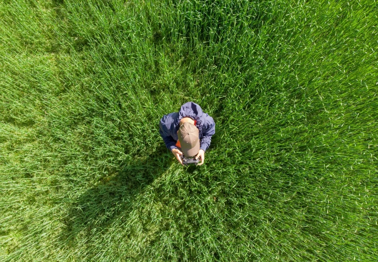 a man standing on top of a lush green field, by Richard Carline, dji top down view, young girl lies on a meadow, realistic wide angle photo, there is tall grass