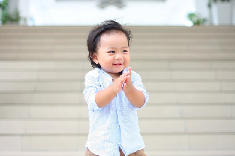 a small child standing in front of a set of stairs, by Bernardino Mei, pexels, happening, waving and smiling, portrait of a handsome, young cute wan asian face, grand finale