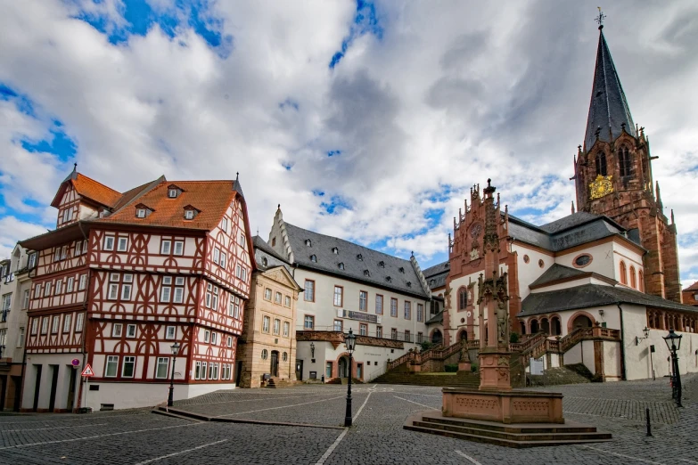 a clock tower sitting in the middle of a town square, a picture, inspired by Rainer Maria Latzke, shutterstock, heidelberg school, shot on a 9.8mm wide angle lens, white houses, red castle in background, three towers