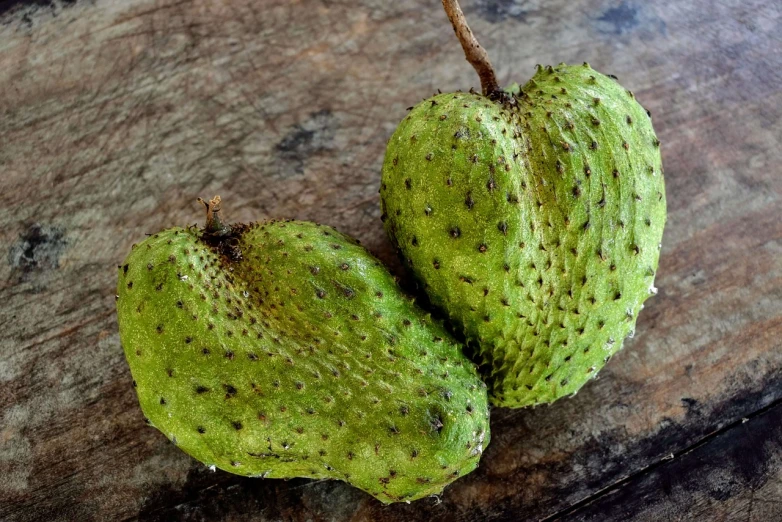 a couple of green fruit sitting on top of a wooden table, sōsaku hanga, coxcomb, 🦩🪐🐞👩🏻🦳, texas, crisp detail