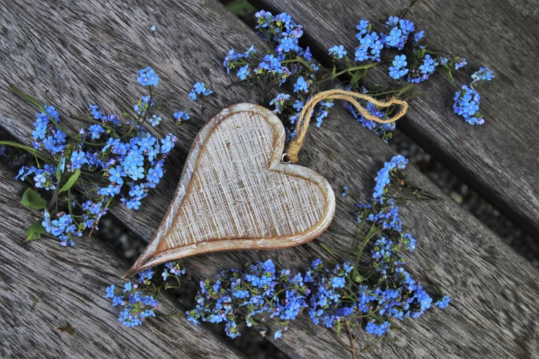 a wooden heart surrounded by blue flowers on a wooden table, a picture, pixabay, folk art, outdoor photo, flax, profile picture, 1647