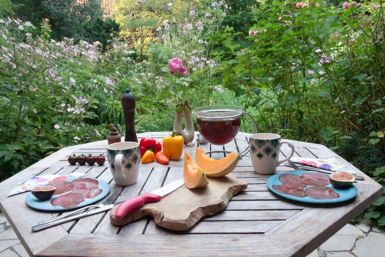 a wooden table topped with plates of food, a still life, inspired by Paul Gustave Fischer, figuration libre, flower garden summer morning, ham, postprocessed, late summer evening