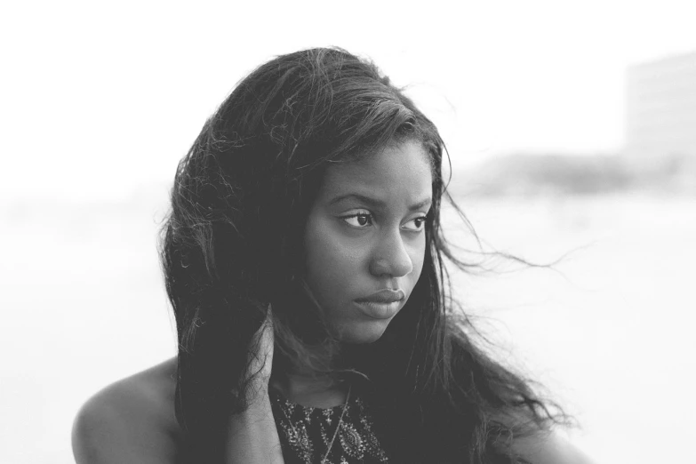 a black and white photo of a woman with long hair, by Lily Delissa Joseph, unsplash, hurufiyya, black teenage girl, looking away from viewer, in the beach, mami wata