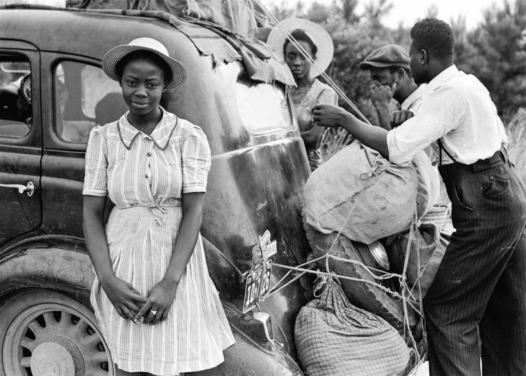 a group of people standing next to a truck, by Dorothea Lange, harlem renaissance, african woman, 🕹️ 😎 🔫 🤖 🚬, great migration, woman holding another woman