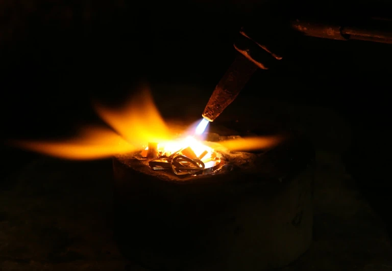 a close up of a metal object with a flame coming out of it, a macro photograph, process art, smoking soldering iron, well lit professional photo, glowing candles, portlet photo