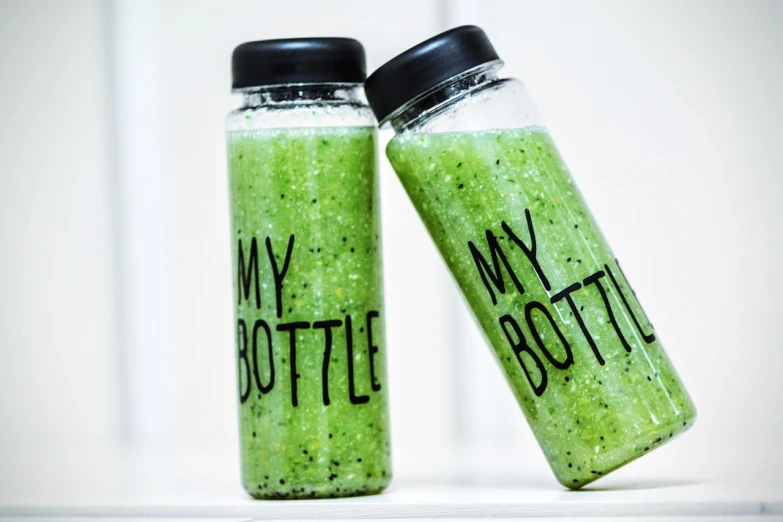 a couple of bottles sitting next to each other, by Matija Jama, green skin!, motivational, trendy food, green sparkles