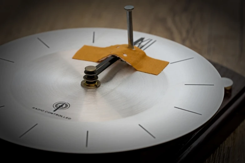 a white clock sitting on top of a wooden table, by Etienne Delessert, kinetic art, movie clockwerk orange, ultra fine detail, sundial, made of brushed steel