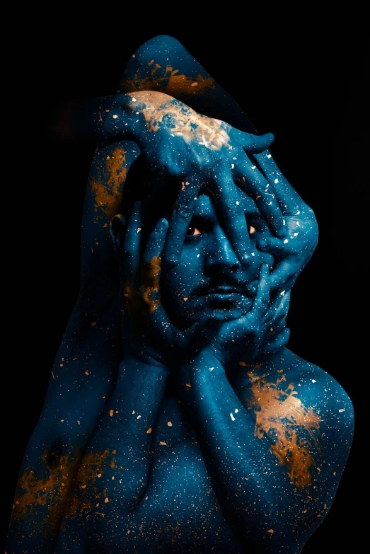 a close up of a person with blue paint on their body, a portrait, art photography, in the universe.highly realistic, resting head on hands, golden bodypaint, philosophical splashes of colors