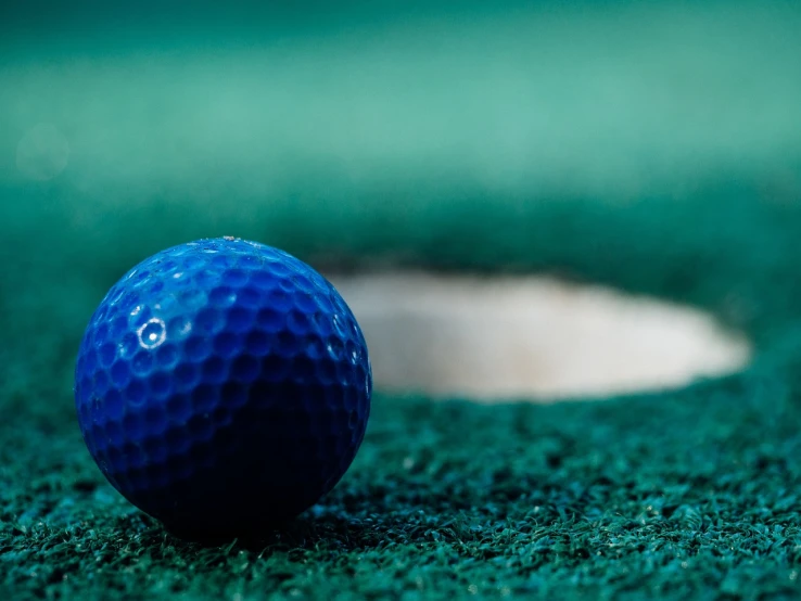 a blue golf ball sitting on top of a green field, unsplash, photorealism, marble hole, avatar image, indoor shot, royal-blue