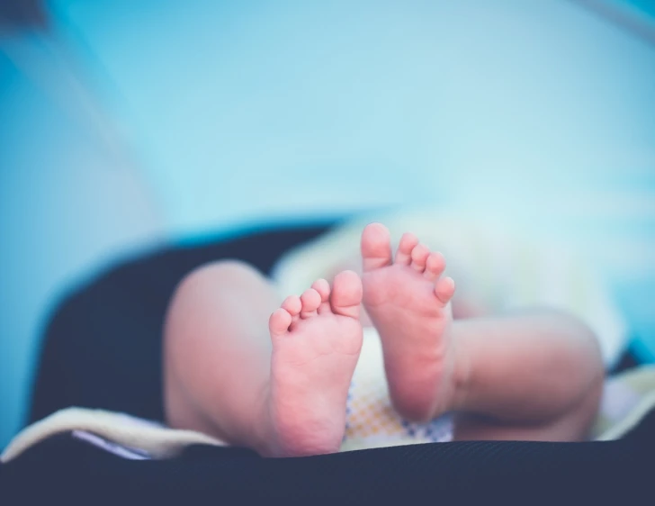 a close up of a baby's feet in a suitcase, a stock photo, shutterstock, incoherents, blurred detail, relaxed. blue background, post processed, bare foot