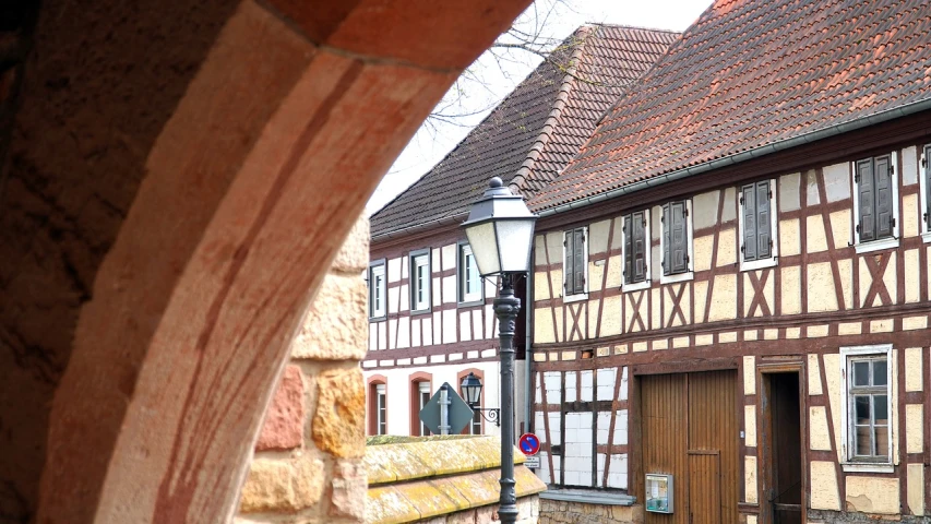 a couple of buildings that are next to each other, a photo, by Karl Hagedorn, romanesque, timbered house with bricks, february), dof:-1, an archway