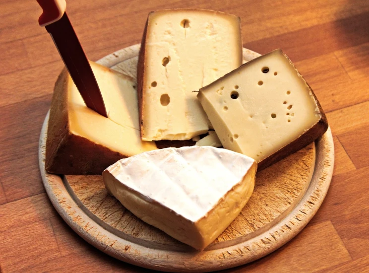 a wooden plate topped with cheese and a knife, by Thomas Häfner, pale smooth, various posed, vanilla, draft