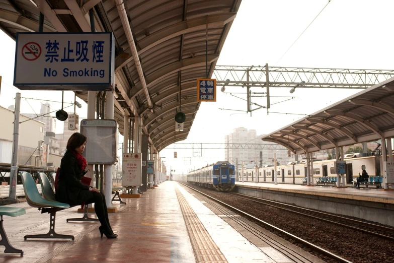 a woman sitting on a bench at a train station, inspired by Zhang Kechun, flickr, high res photo, stock footage, monorail station, morning atmosphere
