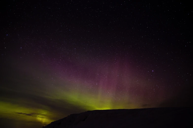 a couple of people standing on top of a snow covered slope, by Jørgen Nash, hurufiyya, northern lights in space, yellow purple green, night photo