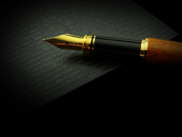 a fountain pen sitting on top of a piece of paper, by Jay Hambidge, pixabay, realism, on black paper, gold, packshot, computer wallpaper