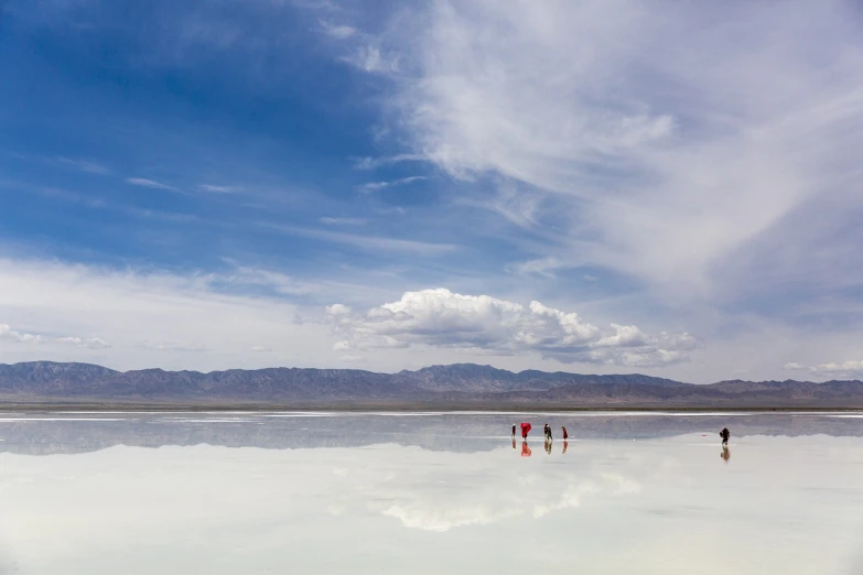 a group of people walking across a large body of water, a photo, inspired by Scarlett Hooft Graafland, shutterstock, minimalism, central california, mirror world, under blue clouds, utah