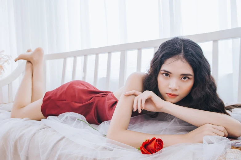 a woman laying on a bed with a rose in her hand, a picture, by Leng Mei, wearing a red outfit, iu, young woman in her 20s, girl in a dress