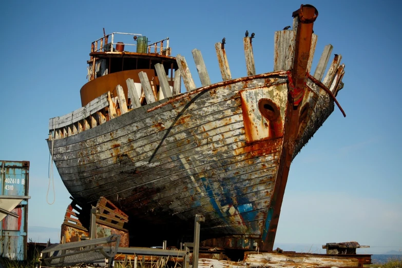 a rusted boat sitting on top of a sandy beach, by Dave Allsop, flickr, mechanical superstructure, under repairs, ivan shiskin, an enormous