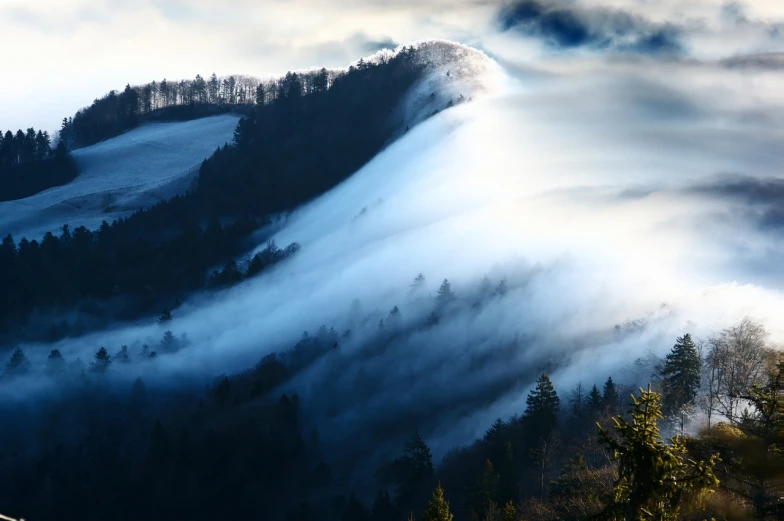 a mountain covered in a thick layer of fog, a picture, by Etienne Delessert, shutterstock, black forest, soft light of winter, cloud vortex, sun ray