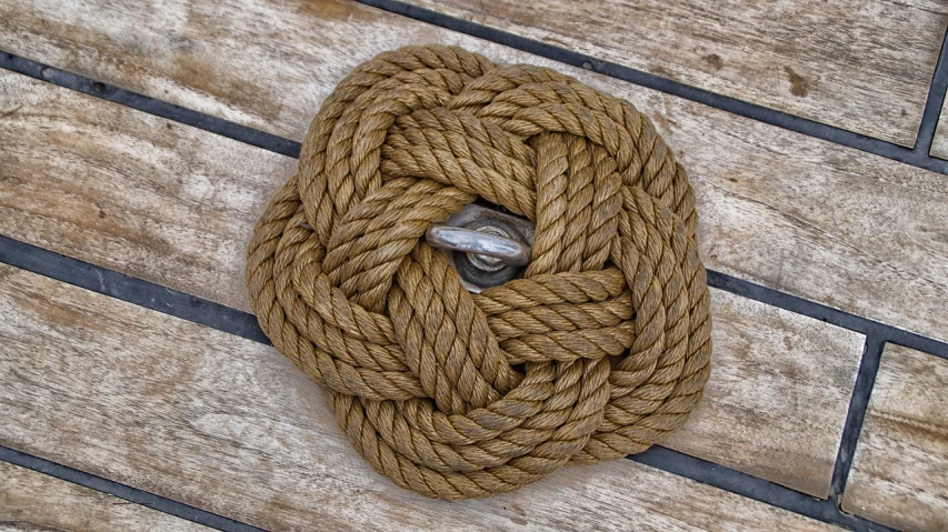 a close up of a rope on a wooden floor, a portrait, inspired by Andy Goldsworthy, flickr, rugged ship captain, rosette, highly detailed”