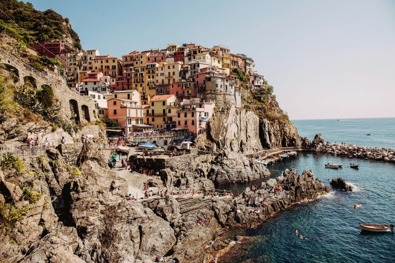 a group of people standing on top of a cliff next to a body of water, by Carlo Martini, pexels, renaissance, brightly colored buildings, rocky coast, 🦩🪐🐞👩🏻🦳, italian looking emma