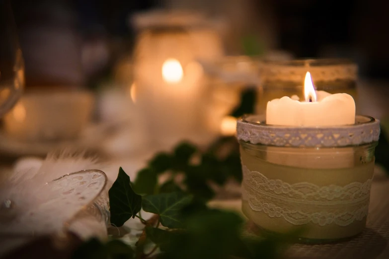 a close up of a candle on a table, a picture, by Maksimilijan Vanka, pexels, dressed in white intricate lace, romantic greenery, partylights, candles!