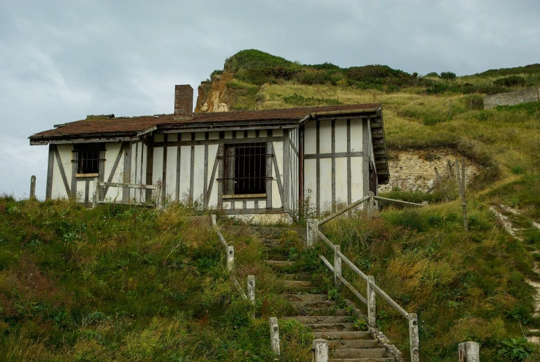 a house sitting on top of a lush green hillside, pixabay, renaissance, storming the beaches of normandy, entrance to abandoned mine, slight overcast lighting, wooden stairs