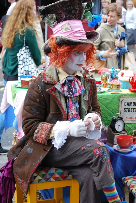 a man dressed as a mad hat sitting on a chair, a photo, alice attends mad tea party, in time square, closeup photo, readhead