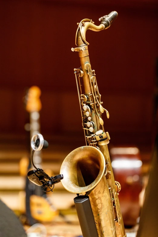 a close up of a saxophone on a table, by David Garner, orchestra, standing microphones, brass and wood mechanisms, jazz age