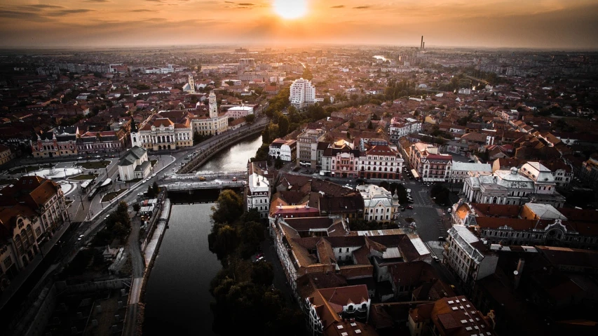 an aerial view of a city at sunset, a picture, by Alexander Bogen, pexels contest winner, renaissance, romanian heritage, building along a river, sun lighting from above, beautiful wallpaper