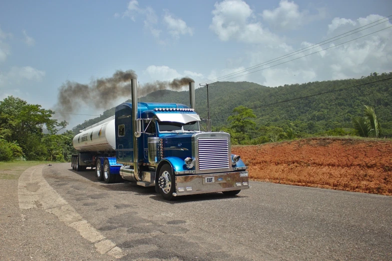 a blue semi truck driving down a rural road, pipe smoke, shiny silver, wikimedia commons, jamaica