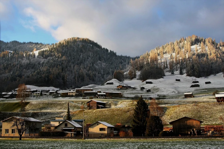 a group of houses sitting on top of a snow covered hillside, by Franz Hegi, flickr, mountain behind meadow, soft morning lighting, biedermeier, haida