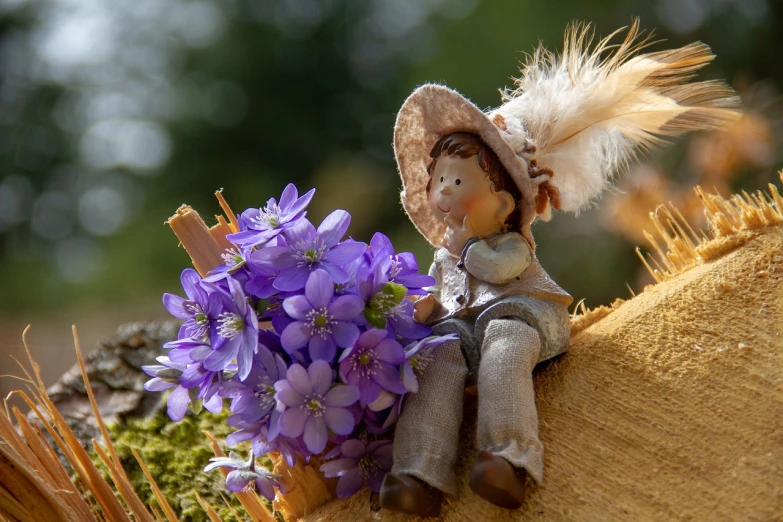 a doll sitting on top of a pile of hay, pixabay contest winner, romanticism, purple flowers, caracter with brown hat, sitting on a log, purple feathers