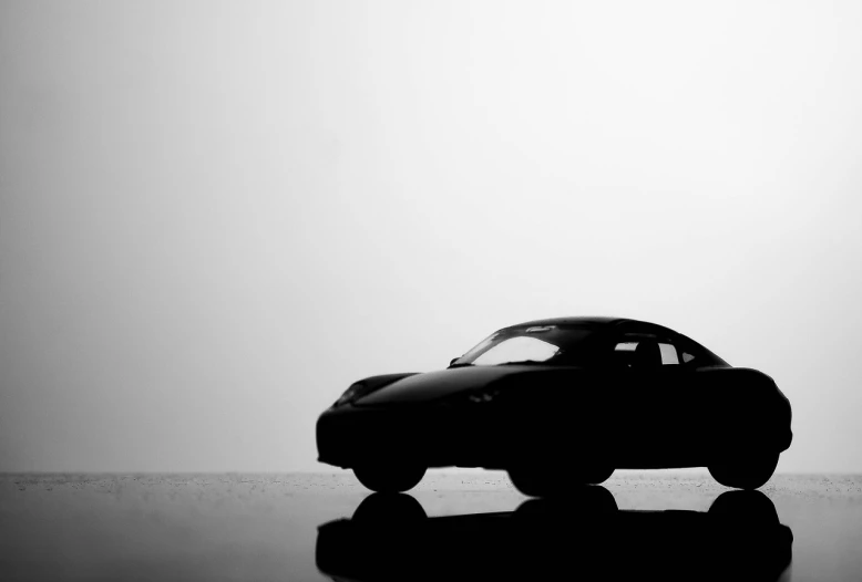 a toy car sitting on top of a table, a black and white photo, unsplash, minimalism, silhoutte, porsche, concept matte, a tvr sagaris