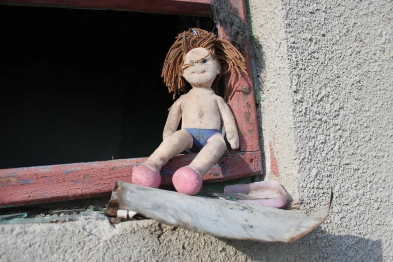 a doll sitting on top of a window sill next to a skateboard, by Anita Kunz, flickr, graffiti, subject made of cracked clay, cottage close up, abandoned prague, plush toy