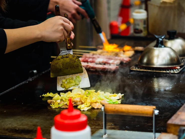 a close up of a person cooking food on a grill, a stock photo, mingei, in tokyo shinjuku, very beautiful photo, flash photo, very accurate photo