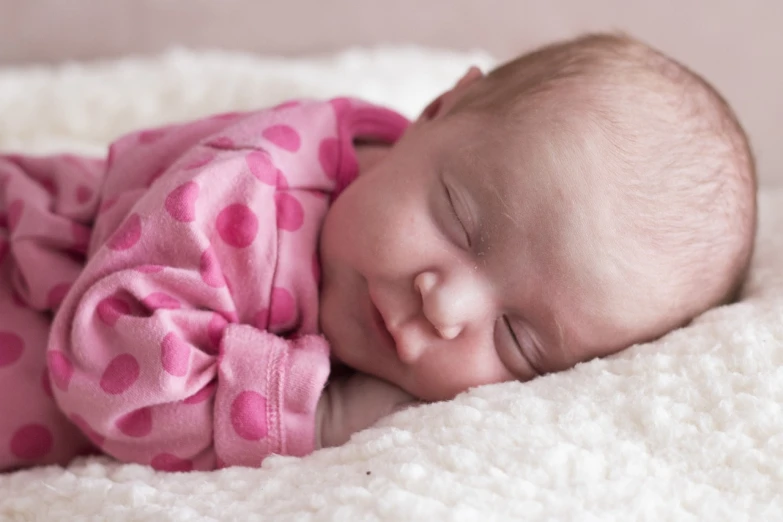 a close up of a baby sleeping on a blanket, a photo, three quarter profile, white and pink cloth, full round face!, shot on 1 5 0 mm