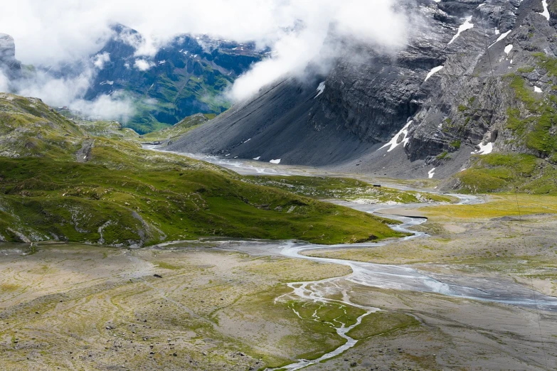 a view of a valley with a mountain in the background, by Werner Andermatt, shutterstock contest winner, erosion channels river, melting clouds, july 2 0 1 1, switzerland