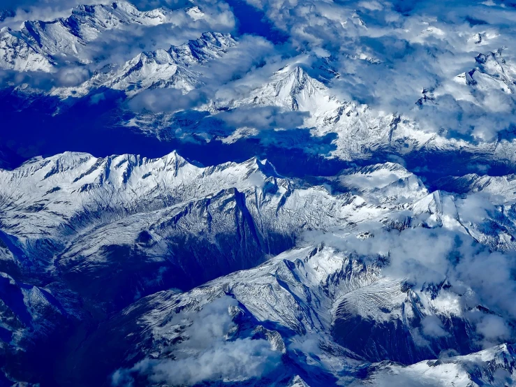 a view of snow covered mountains from an airplane, by Cedric Peyravernay, pexels, precisionism, mount doom, several continents, very very well detailed image, high quality details